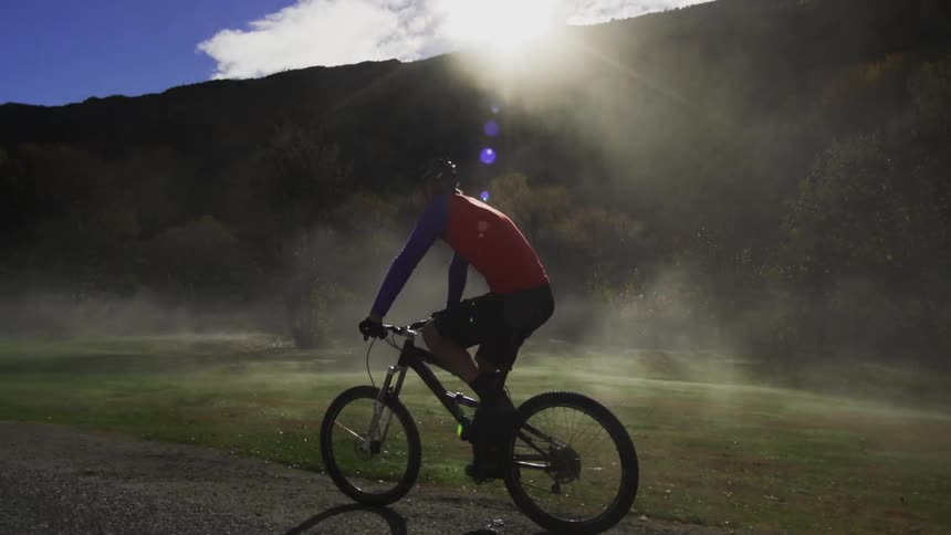 Man in red shirt rides bicycle at sunset