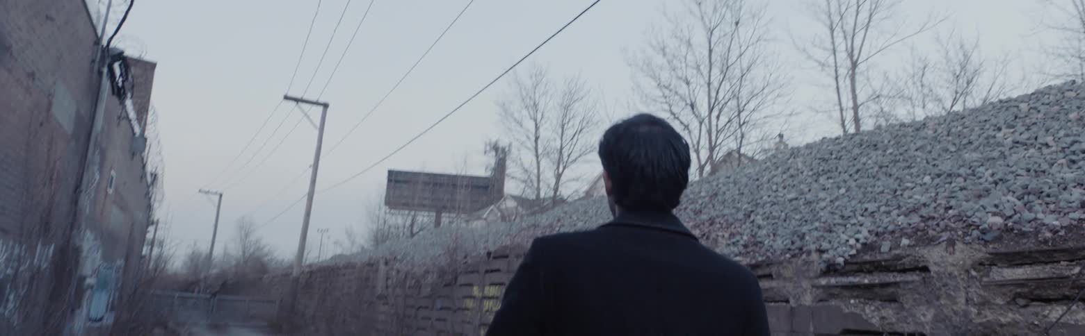 A man walks down a graffiti filled alley