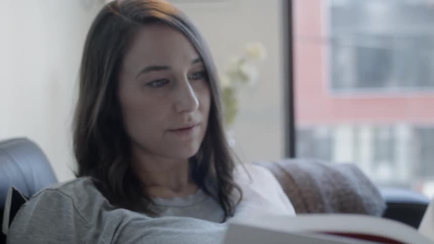 Woman sits on a couch reading a book