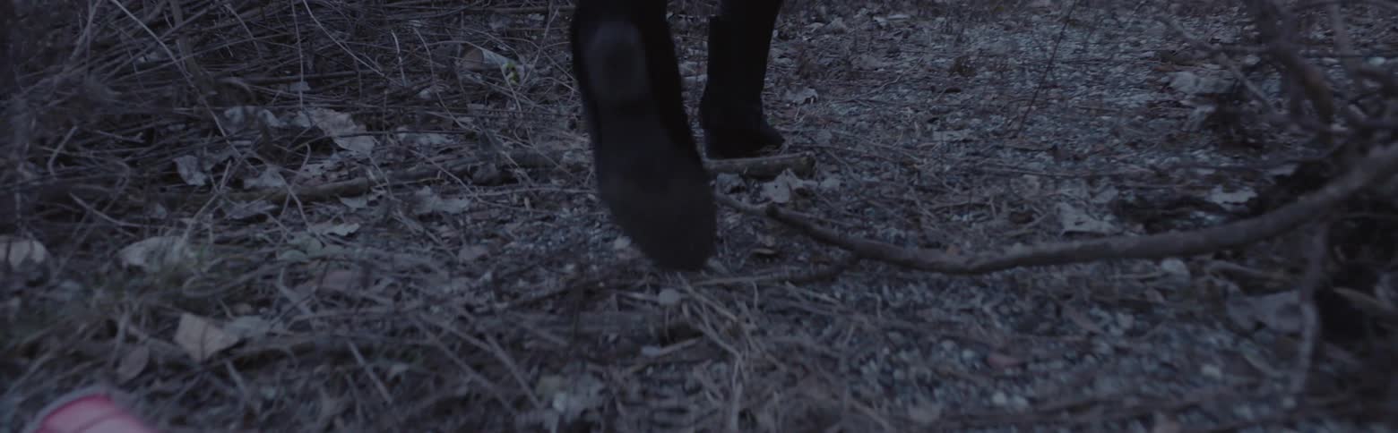 A woman in ankle boots walks through the brush
