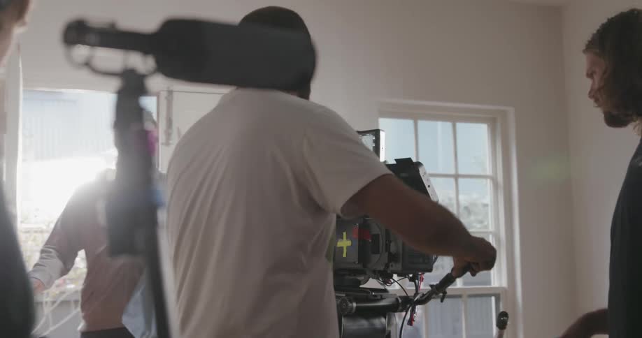Several men recording with large cameras in a house on a sunny day