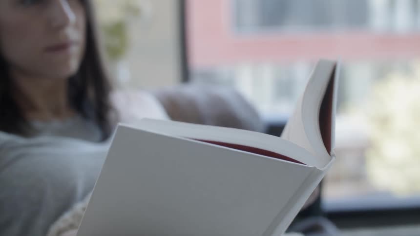 Woman sitting reading a book and turning the page