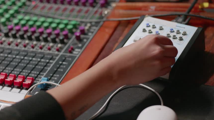 A woman adjusts knobs on a mixer board