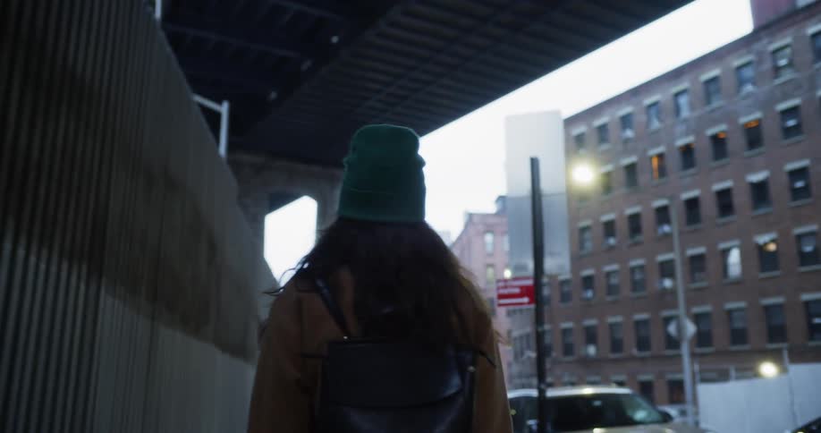 Woman walks through an archway of a building on a cold day