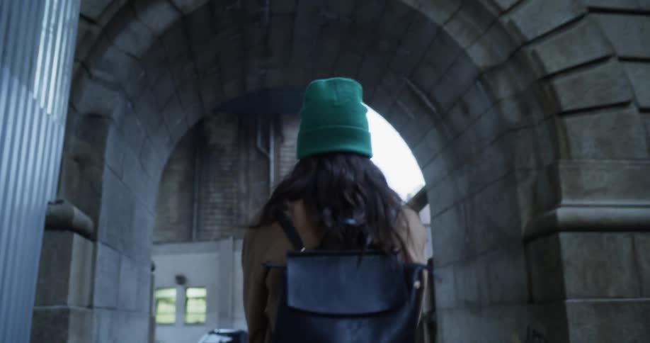 Woman walks through an archway in a city