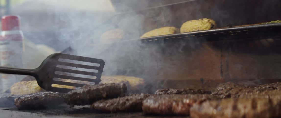 A chef flips burgers on the grill