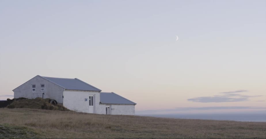 White building sits near a field under a blue sky