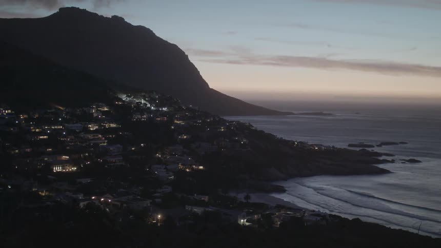 Waves roll into shore near an illuminated city
