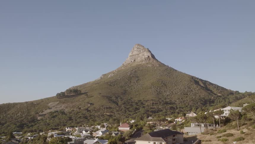Mountain stands tall near a village under a blue sky