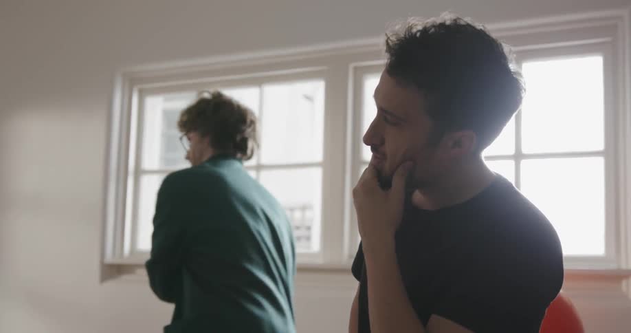 A man catches a ball being thrown inside the house