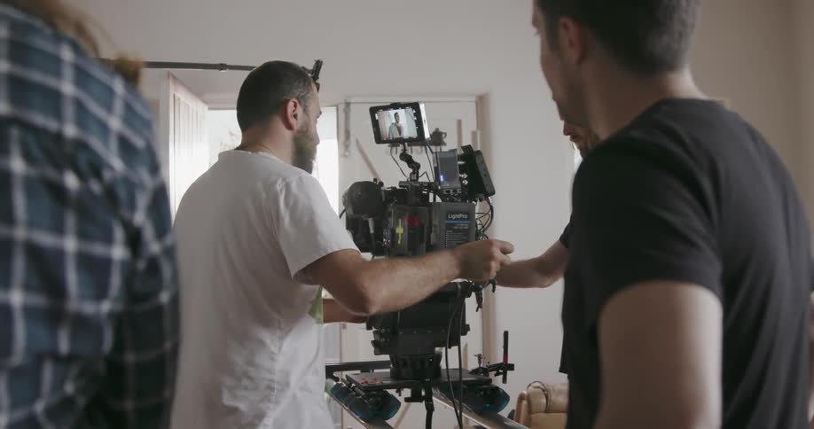 Man pushes a video camera as other men watch