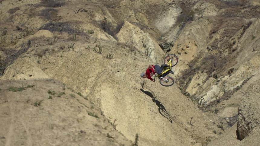Man doing a flip on his bike on a sand hill and falls down the hill