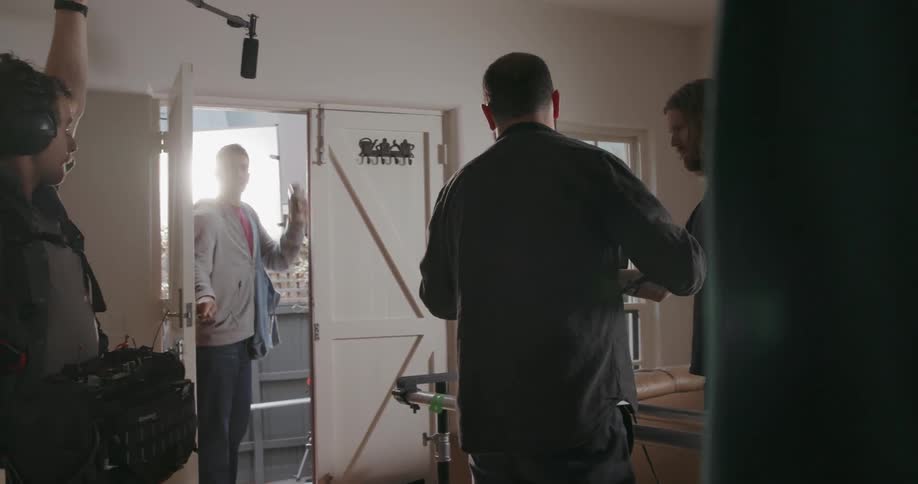 Several men with camera equipment film in a house