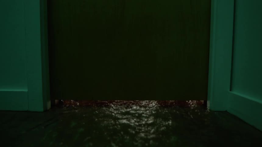 Water rushes in a building from underneath a door