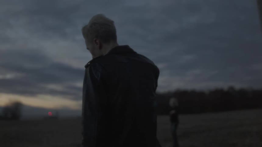 A man and woman walk in the field at dusk