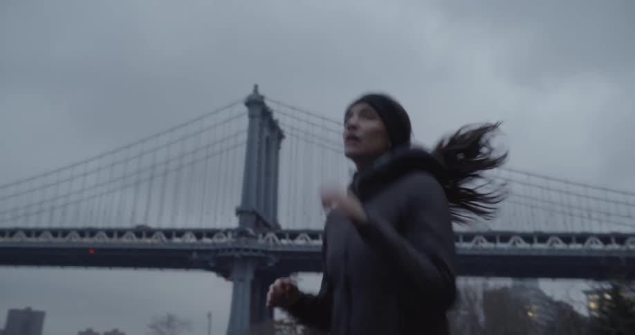 Woman jogging near a bridge on a cloudy day
