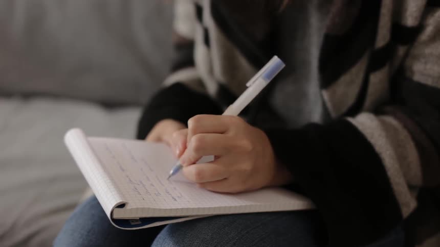 Person sits on a couch writing on a notepad