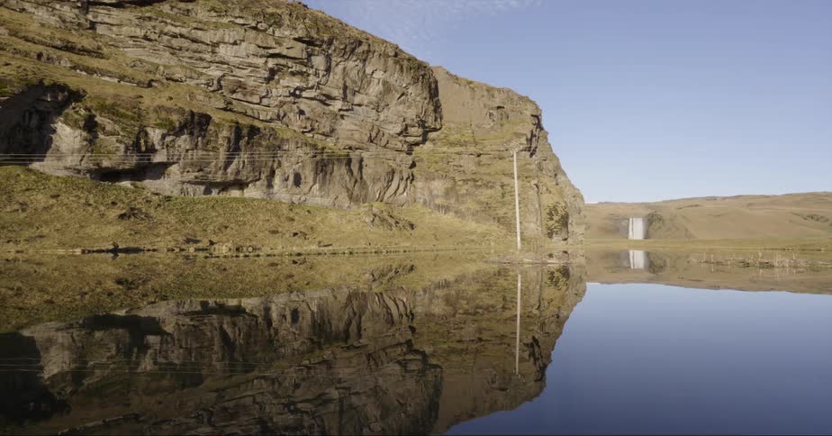 A desert oasis is reflecting nearby cliffs on a sunny day