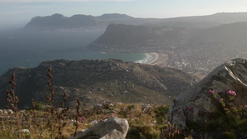 Haze is lingering in the air over a community on a rugged coastline during the day