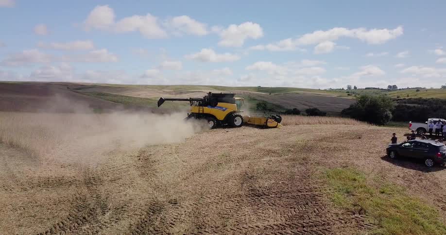 Farm equipment cuts down grass and kicks up dust