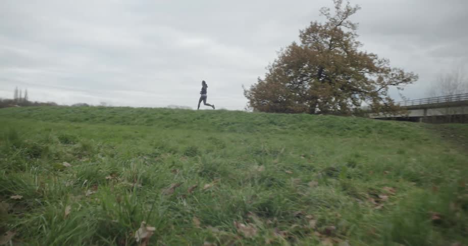 A person is jogging up the hill on a cloudy day