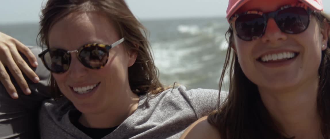 Women are smiling while riding on boat on sunny day