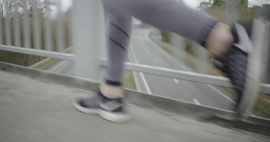 Woman jogs on a bridge over a highway