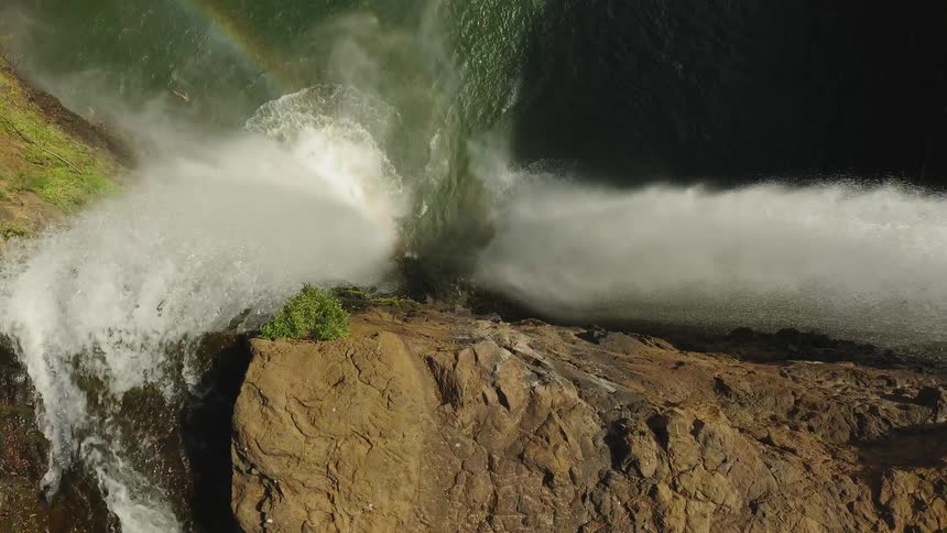 A flowing waterfall creates a rainbow when it splashes into the basin