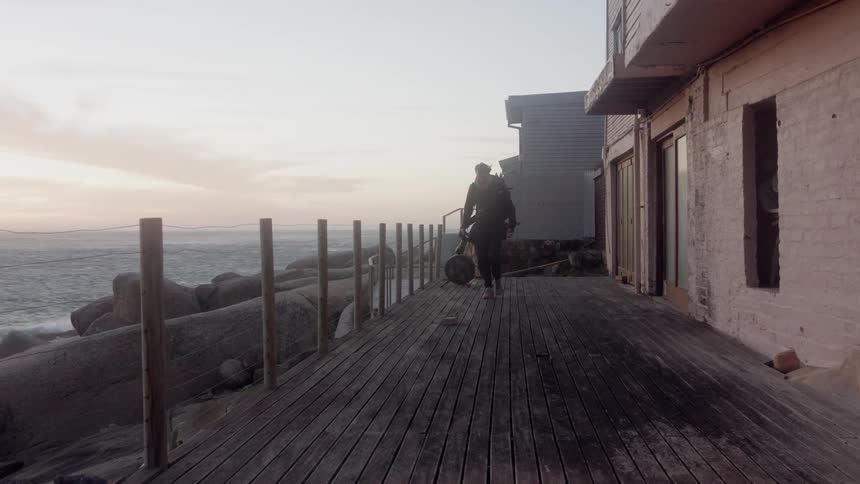 Man walks next to a building as he carries a camera