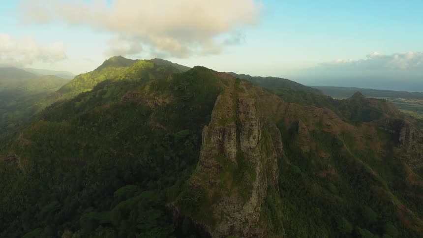 Clouds float over grass covered mountains