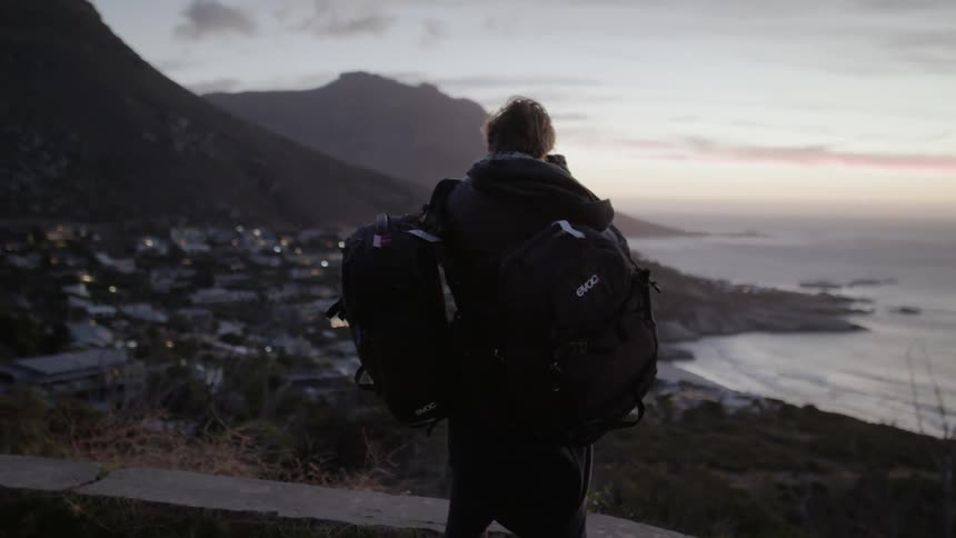 A man with two backpacks is taking photographs