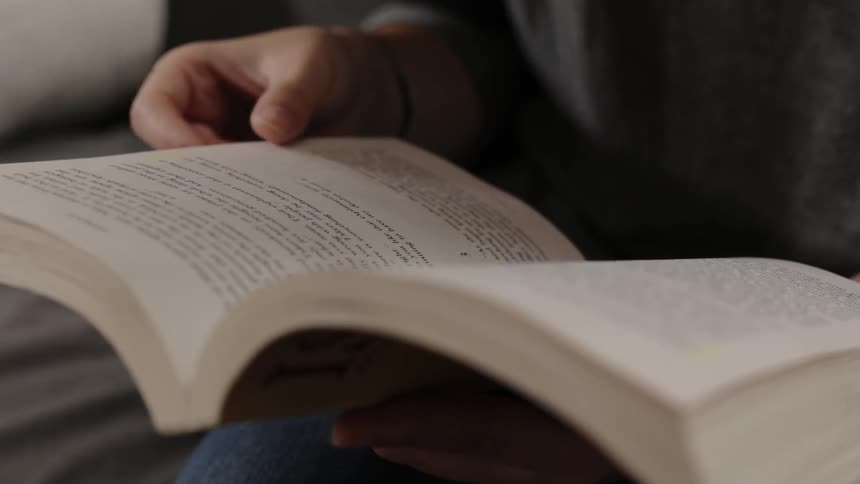 Person turns pages of a book on their lap