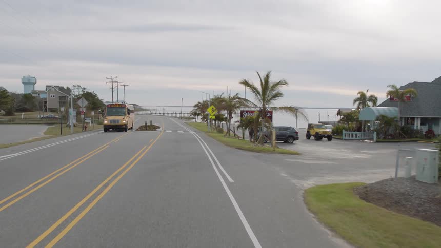 Vehicles drive down a street on the outskirts of a city