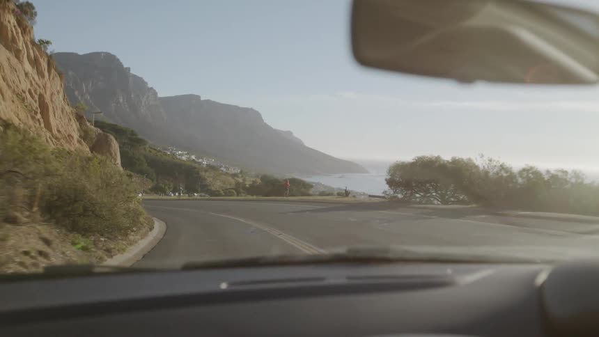 Vehicle drives down a winding country road near a body of water