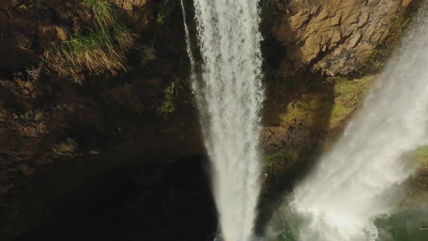 Waterfall flowing off edge of rock cliff on sunny day