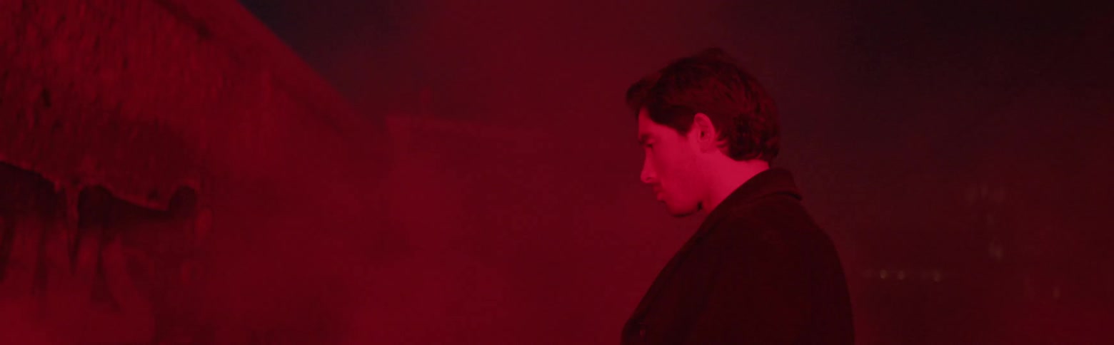 A man walks on a city street through fog and red light
