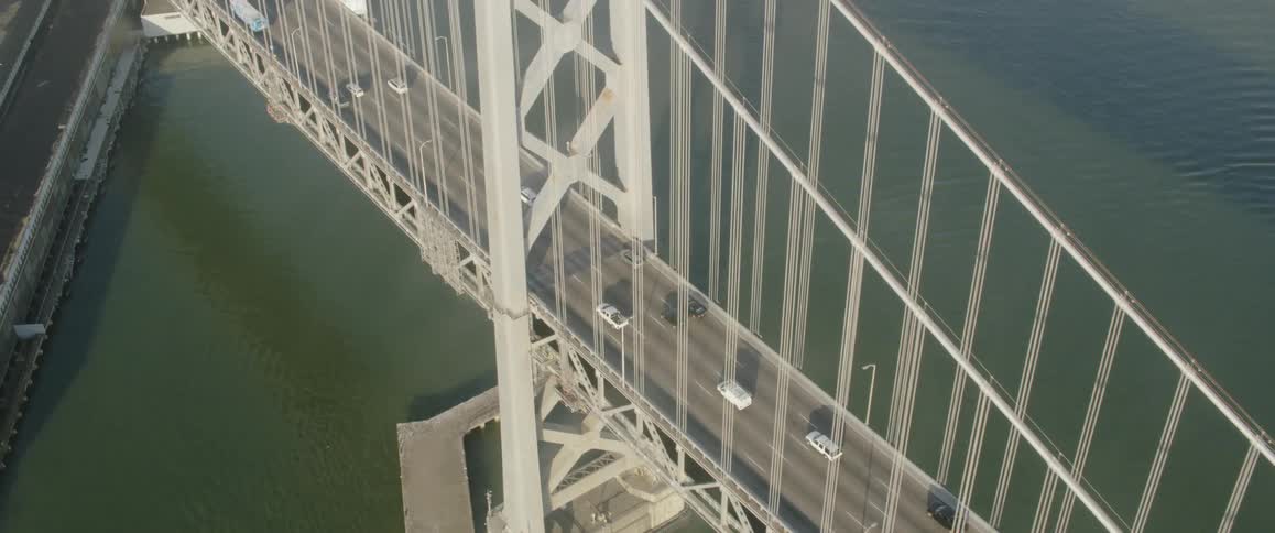 Many vehicles drive on a bridge over a large body of water