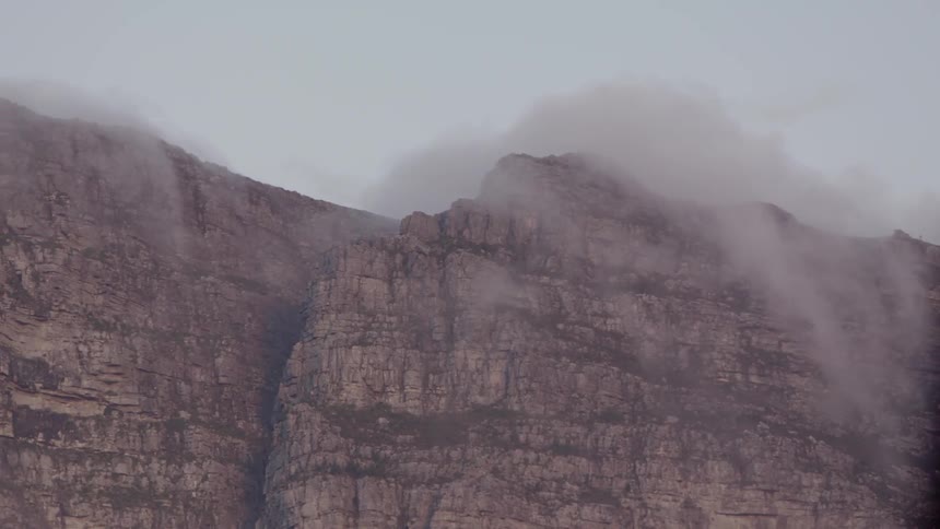 Clouds float above a rocky cliff