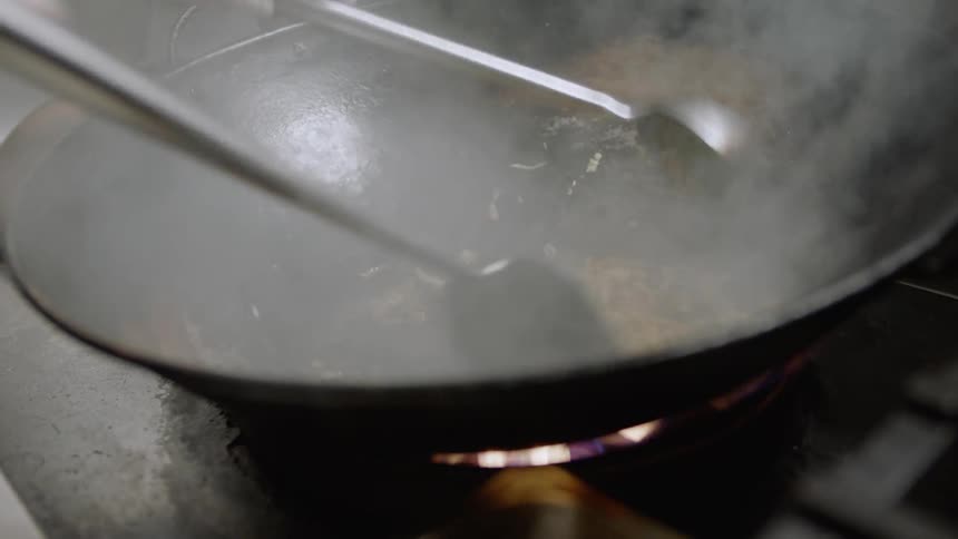 A person is cooking food in a wok