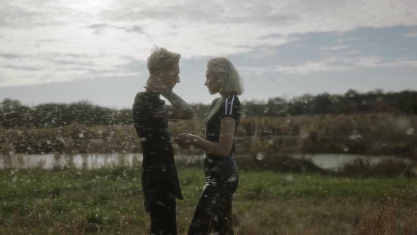 Man and woman touch as they stand in a field