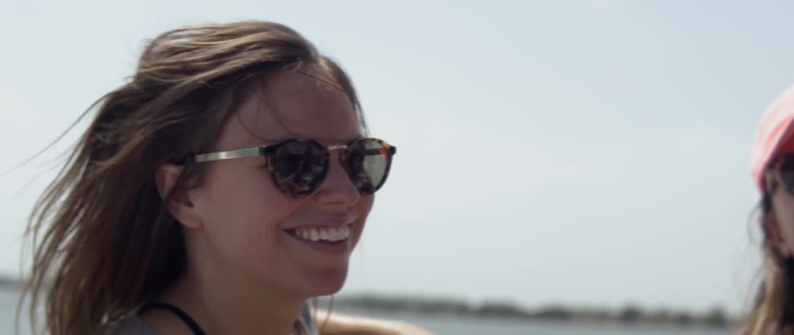 A woman sitting on a boat smiles on a sunny day