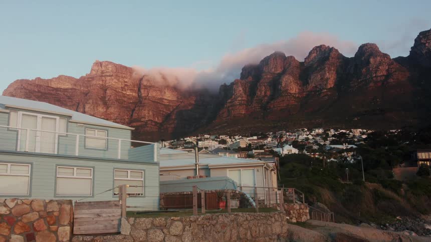Houses sit under the blue sky near the mountains