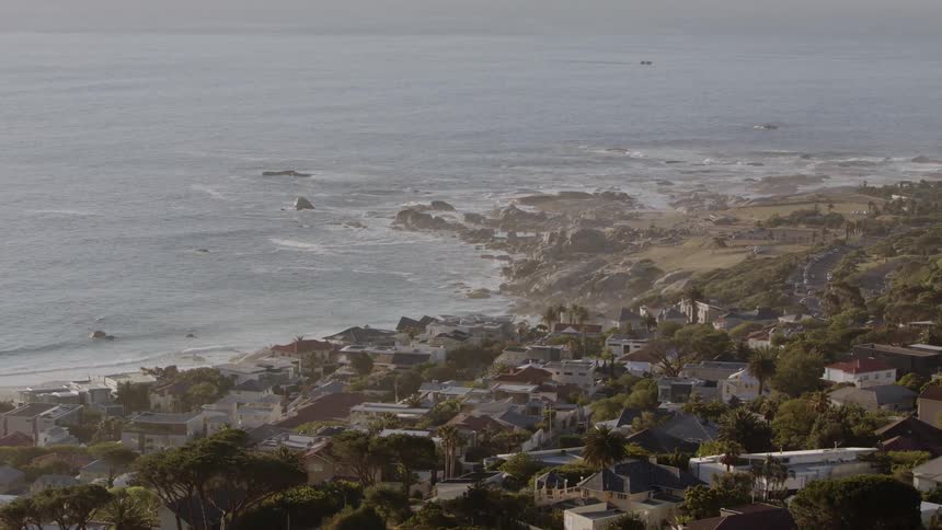 Water splashes onto a beach next to a city