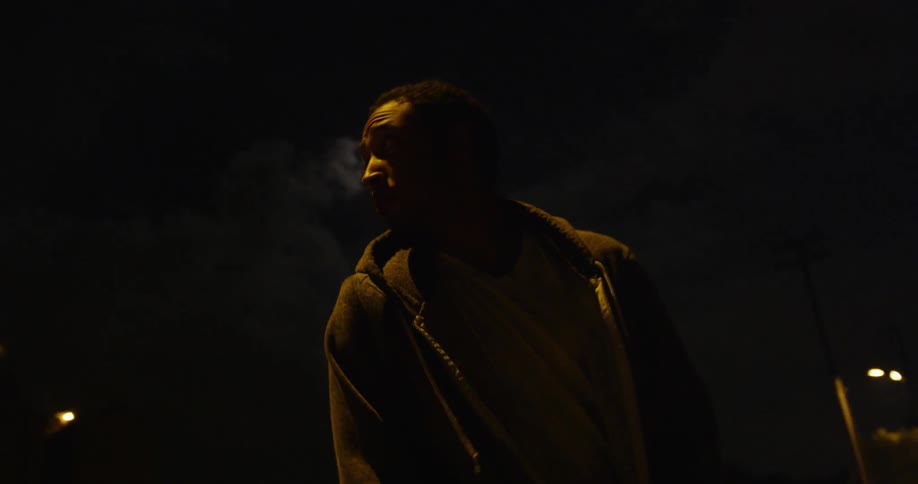 Man is looking behind him as he walks on street at night