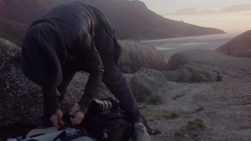 Person leans over putting a phone in a bag outside on a windy day