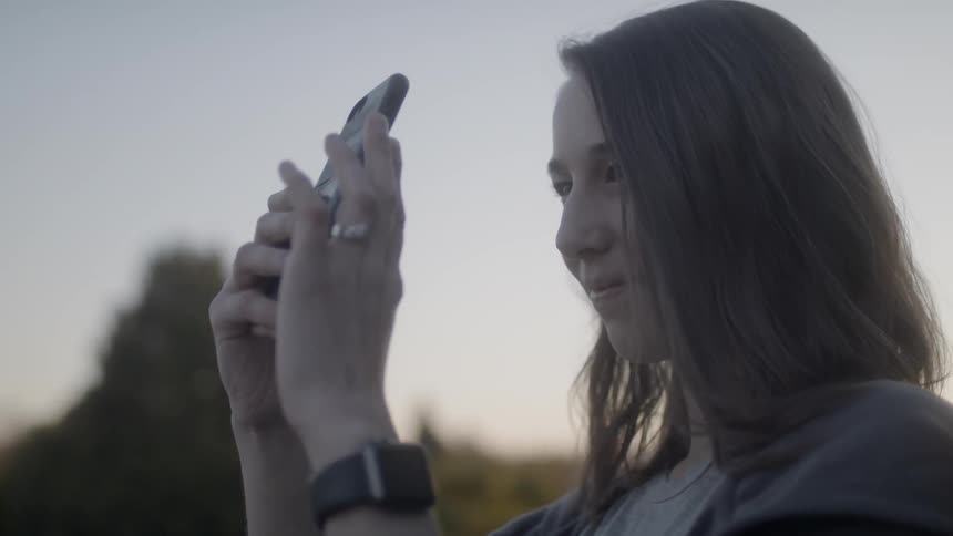 Smiling woman records nature with her phone