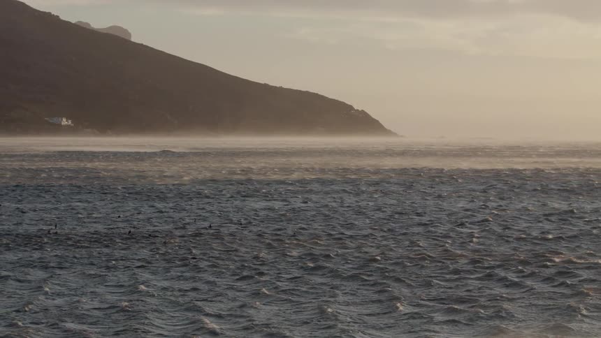 Mist is blowing off the ocean surface on a windy day