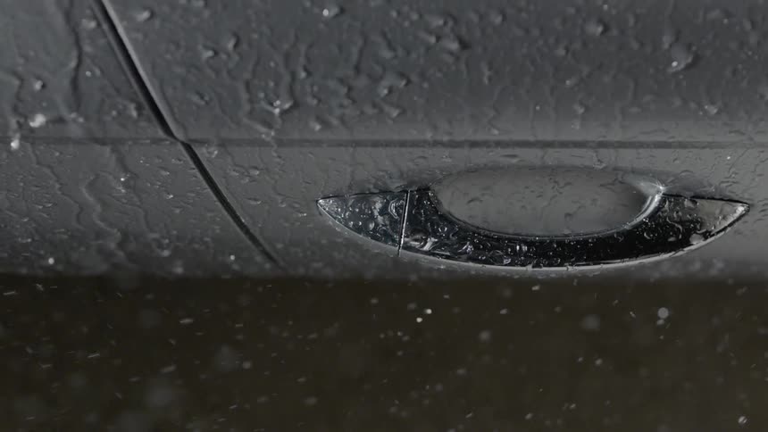 Rain falls onto a car door