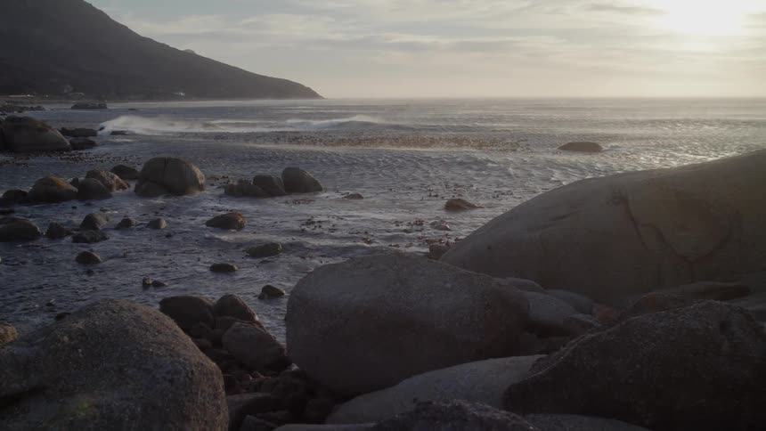 The tide flows towards the rocky shore
