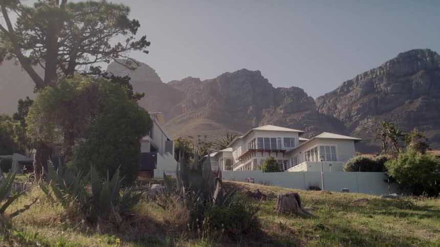 White building sits near the trees in front of a mountain